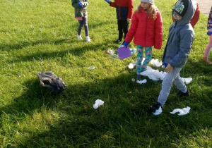 dzieci podnoszą śmieci z trawnika